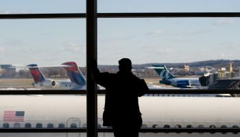 A man looks out the window at airplanes