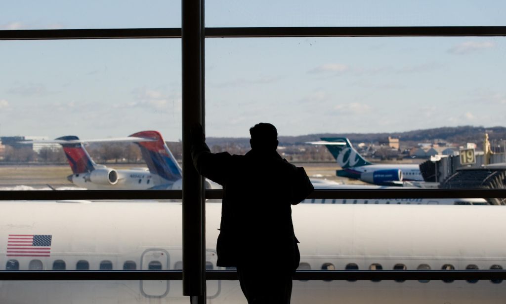 A man looks out the window at airplanes