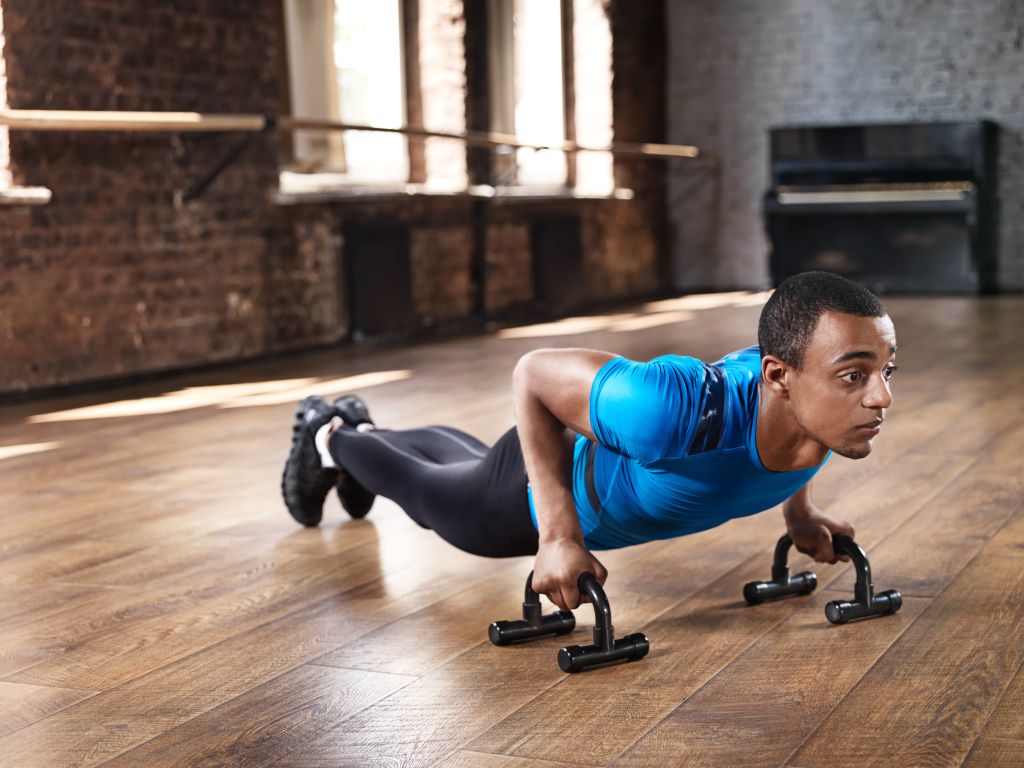 Muscular man doing push ups in lofty gym