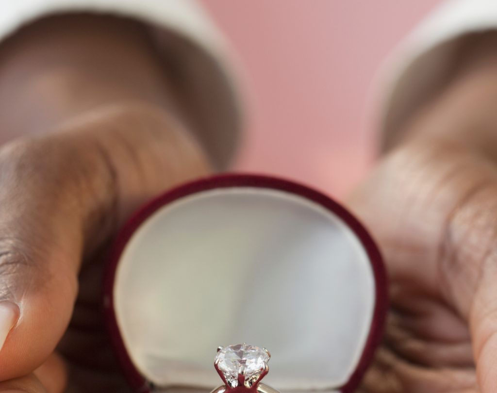 African woman holding engagement ring in box