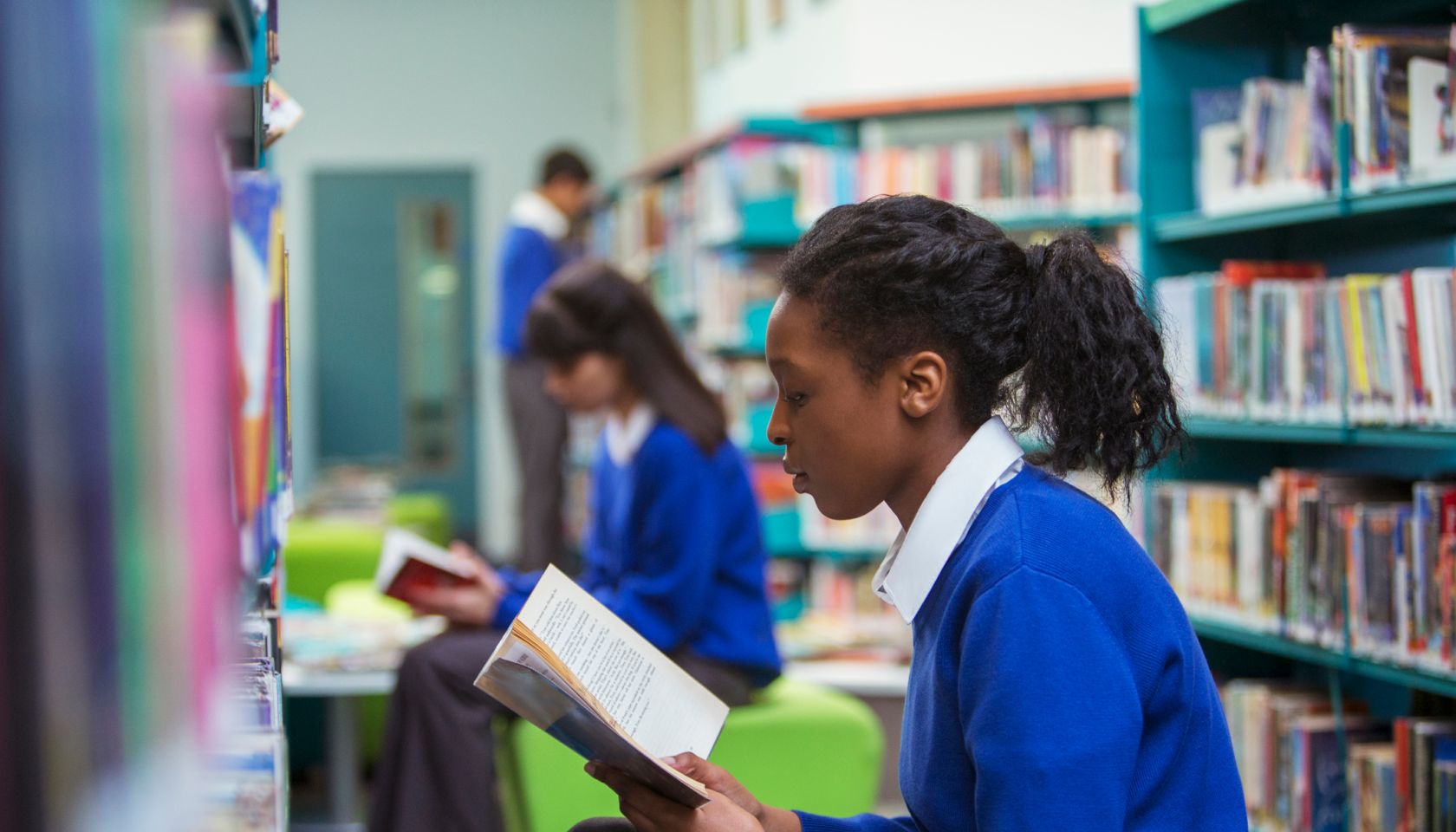 High School students sitting and reading book in library