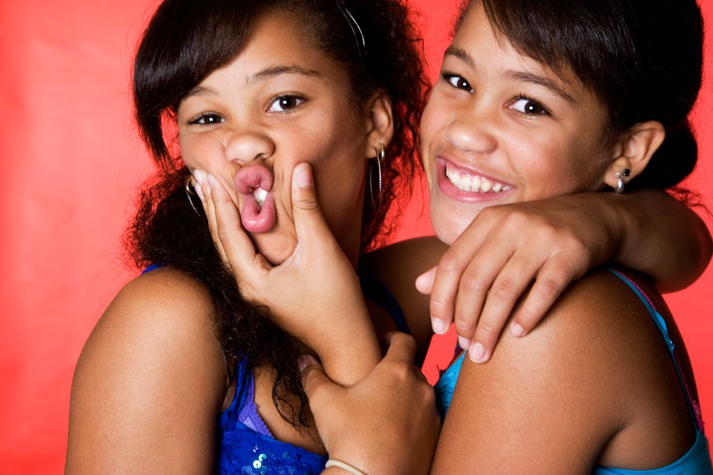 Mixed race teenage twin girls making faces