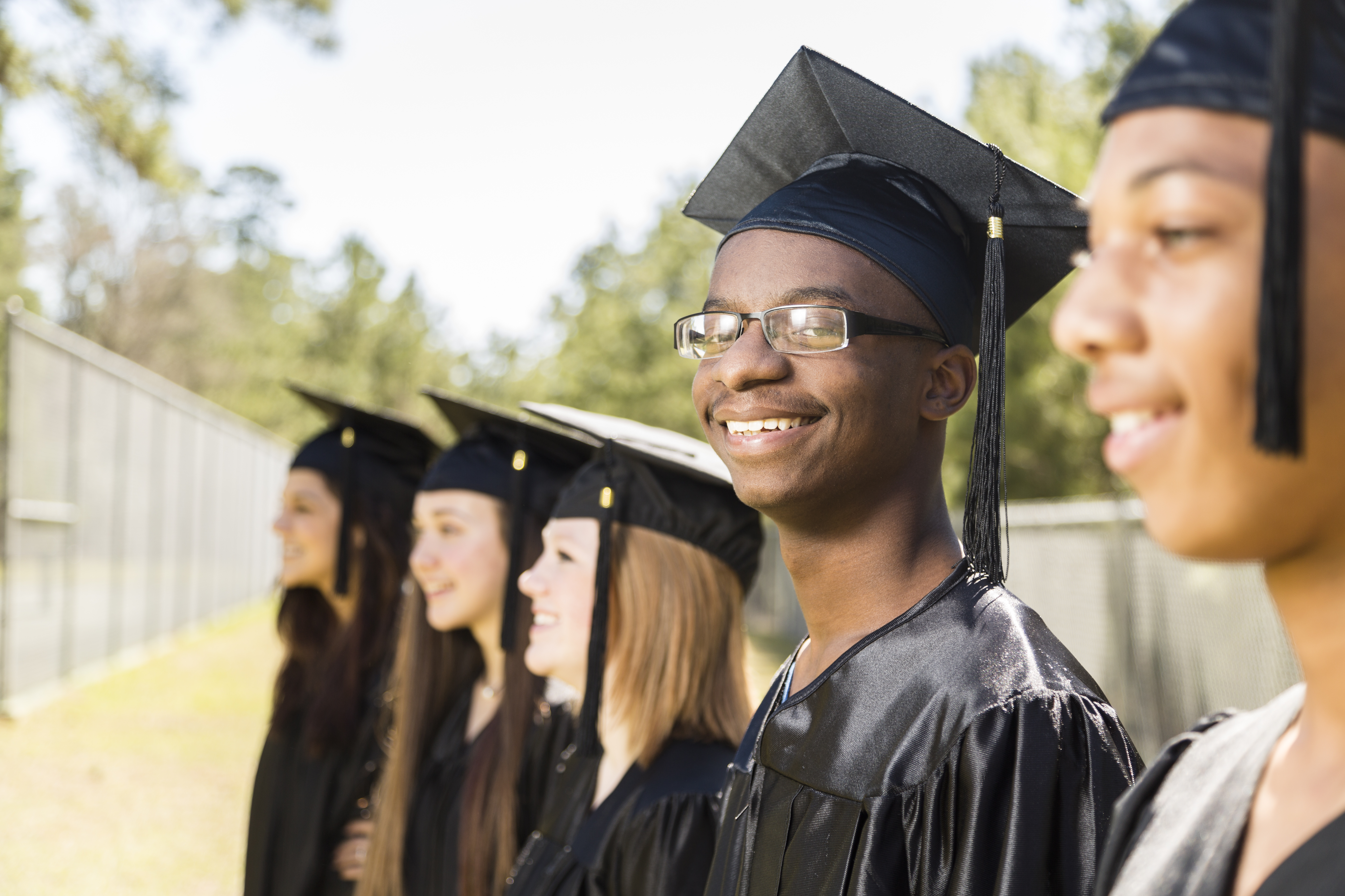 African descent college, high school student waits at graduation.