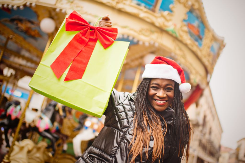 Young African woman in Santa hat with shopping bag