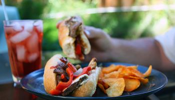 Cheese steak sandwich with red peppers and chips