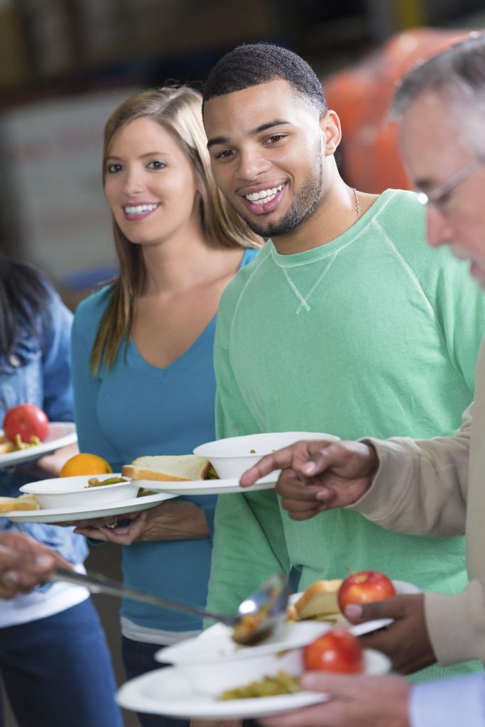 Diverse people eating meal together at community food bank