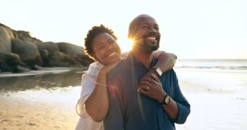 Couple, hug and happy on beach with love, bonding and sunset for holiday, vacation and relationship. Black people, man or woman with embrace, smile and romance by ocean or sea for travel or adventure