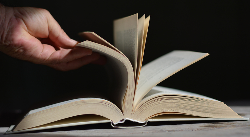 A hand opens a book
