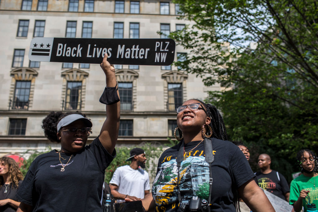 A woman holding a sign Black Lives Matter written on it...